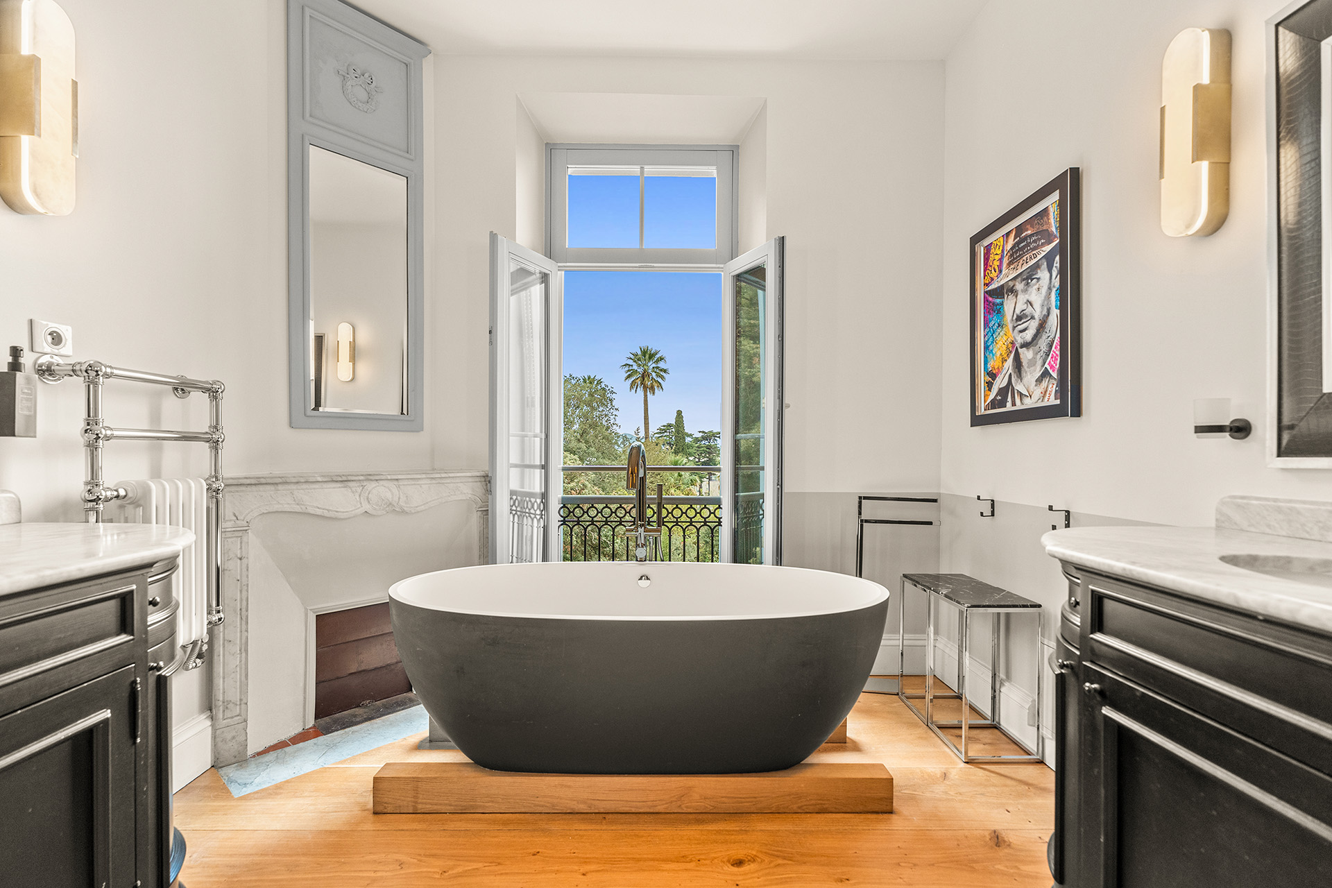 luxury-bathroom-bathtub-cannes Luxury bathroom at Château Les Alouettes featuring elegant black accents, freestanding bath and balcony views overlooking lush gardens in Cannes.