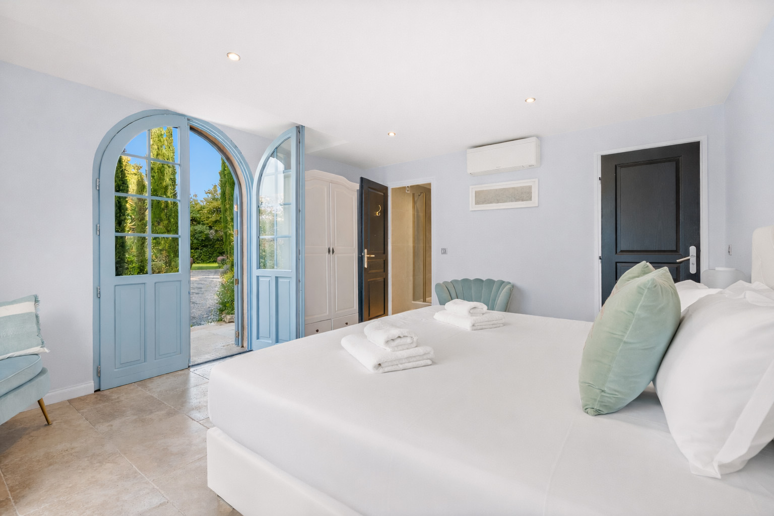 luxury-bedroom-suite-blue-french-door-cannes Bright luxury bedroom with French doors, elegant furnishings and garden views at Château Les Alouettes Cannes.