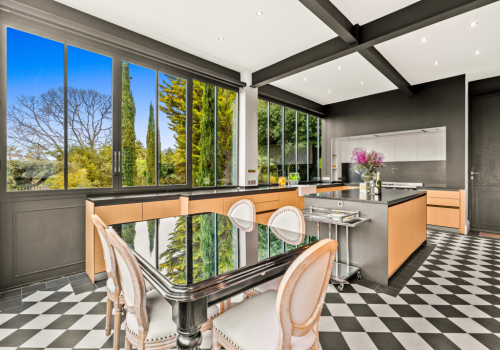 luxury-kitchen-garden-view-bright-cannes Elegant dining area with large open windows overlooking palm trees and gardens at Château Les Alouettes luxury villa in Cannes.