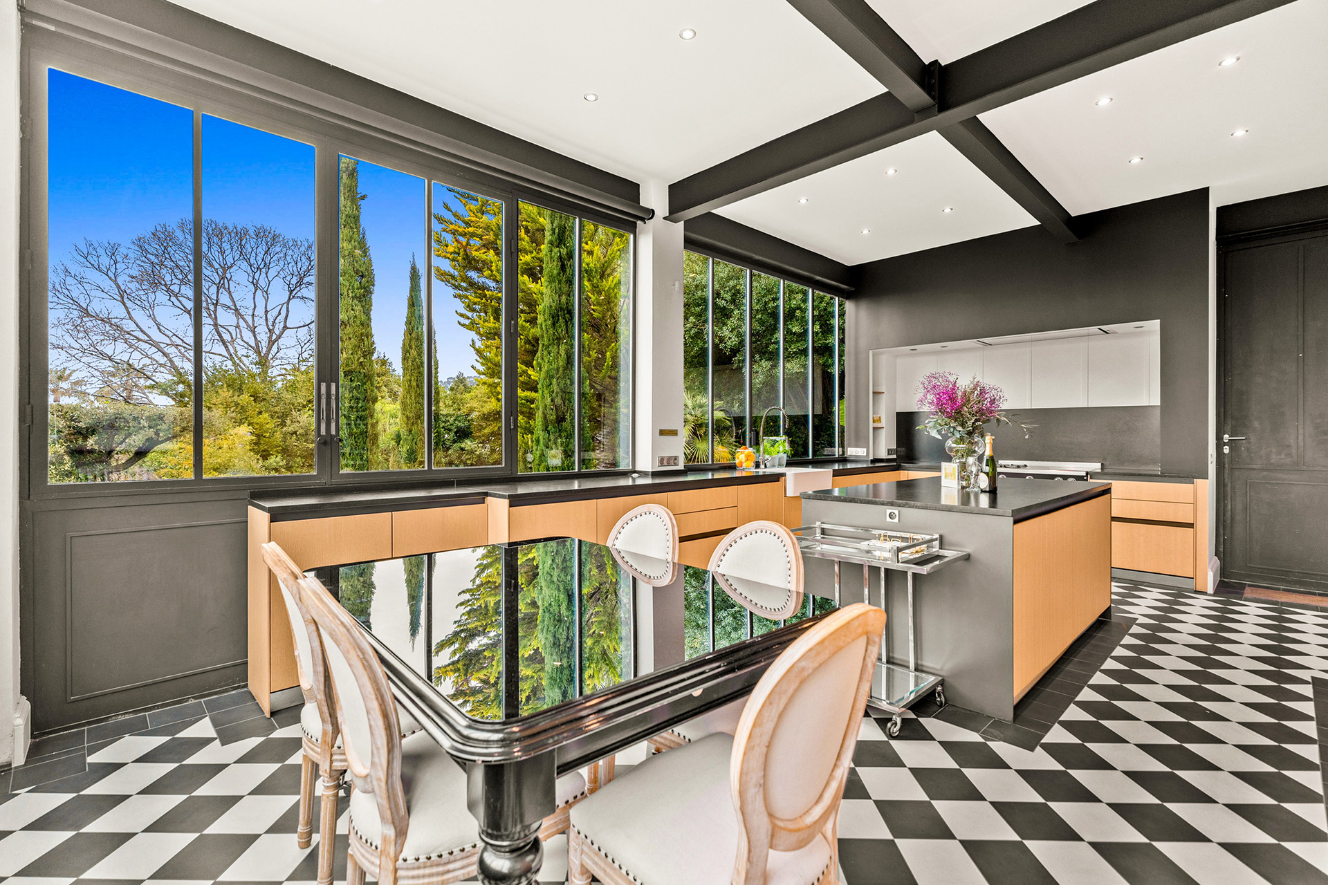 luxury-kitchen-garden-view-bright-cannes Modern luxury kitchen with black island, panoramic windows and elegant contemporary interiors at Château Les Alouettes Cannes.