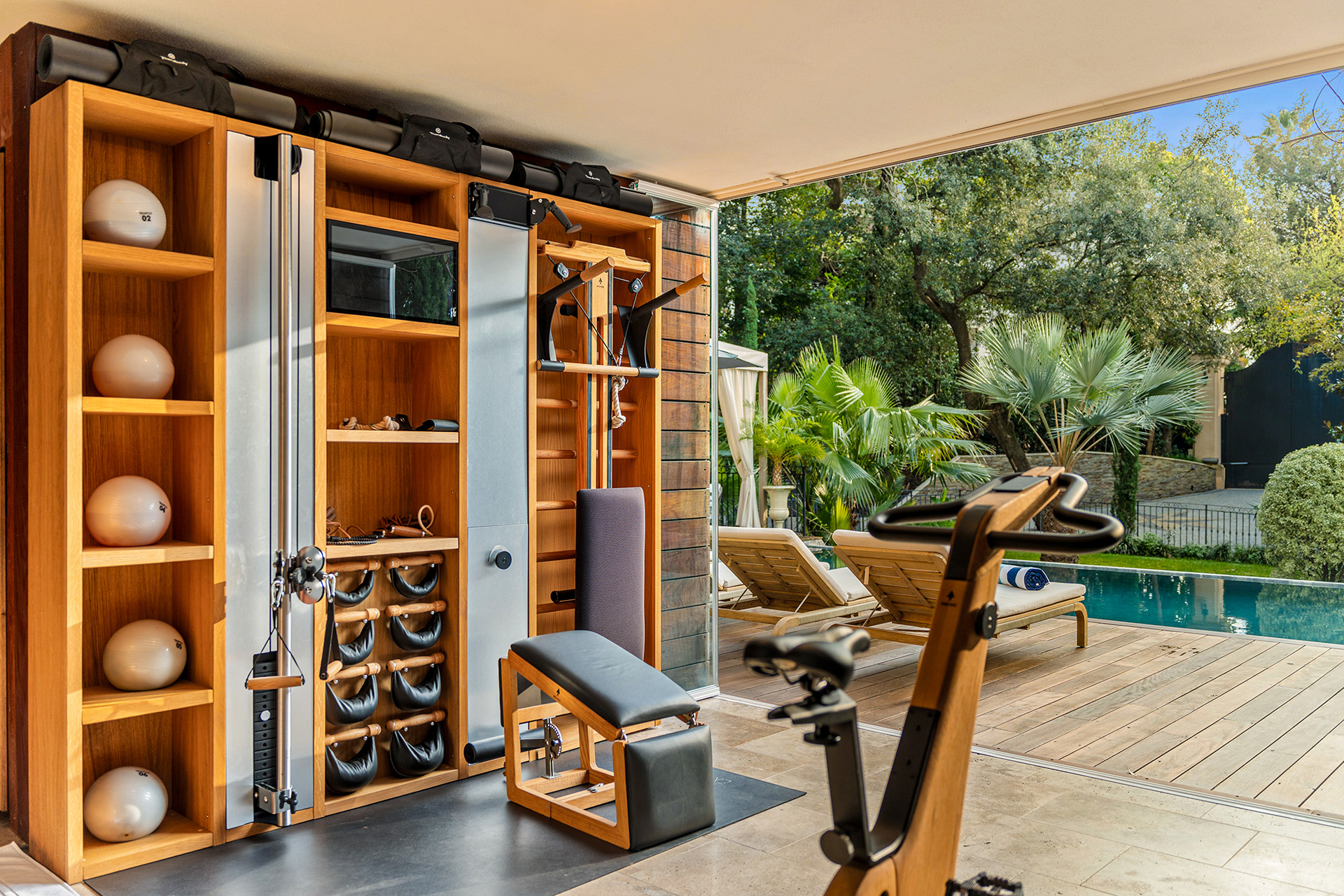 luxury-library-shelves-pool-view-cannes Luxury fitness and wellness room with premium Pilates and training equipment at Château Les Alouettes villa in Cannes.